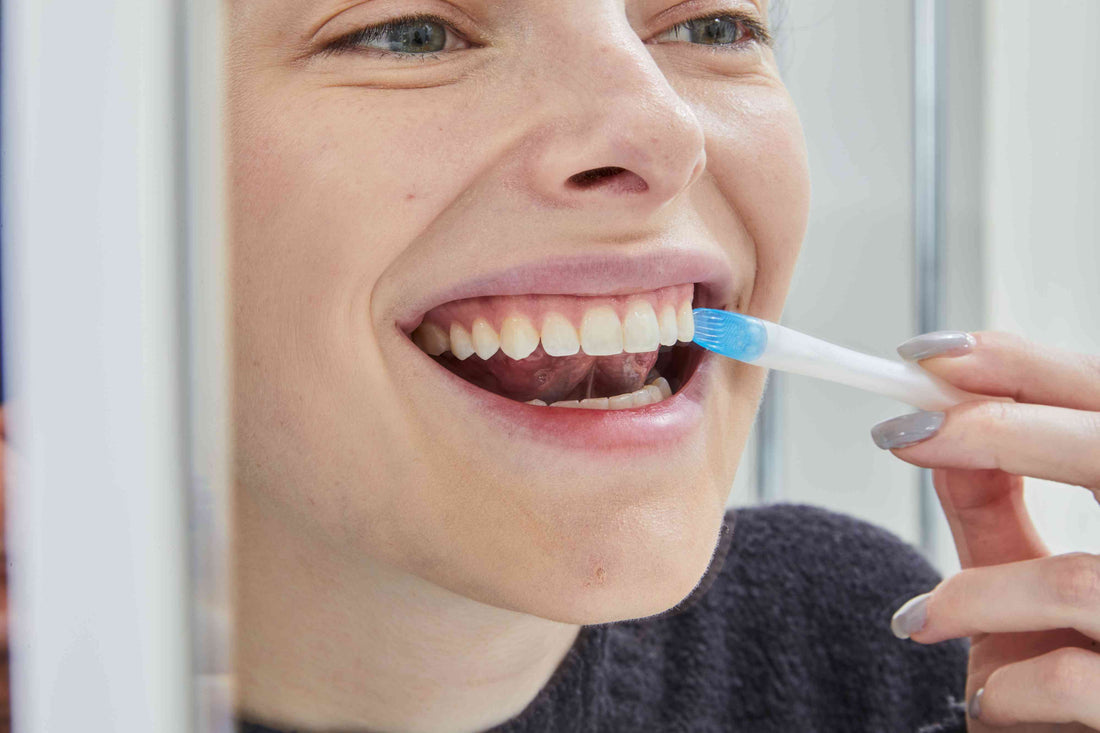 Un chico sonriendo frente al espejo con unos dientes blancos y radiantes gracias al blanqueamiento dental de Shinoi Labs