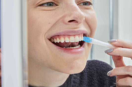 Un chico sonriendo frente al espejo con unos dientes blancos y radiantes gracias al blanqueamiento dental de Shinoi Labs