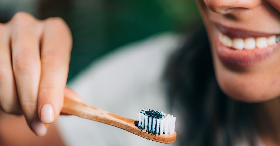 foto de una mujer sujetando un cepillo de dientes con unos polvos azules.